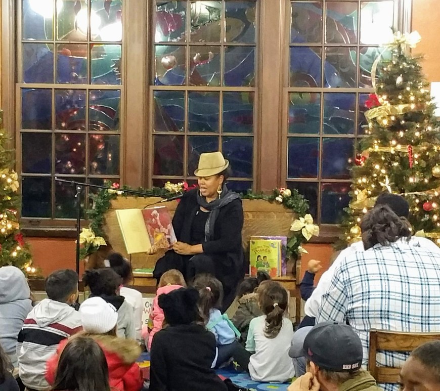 woman wearing hat reading to audience